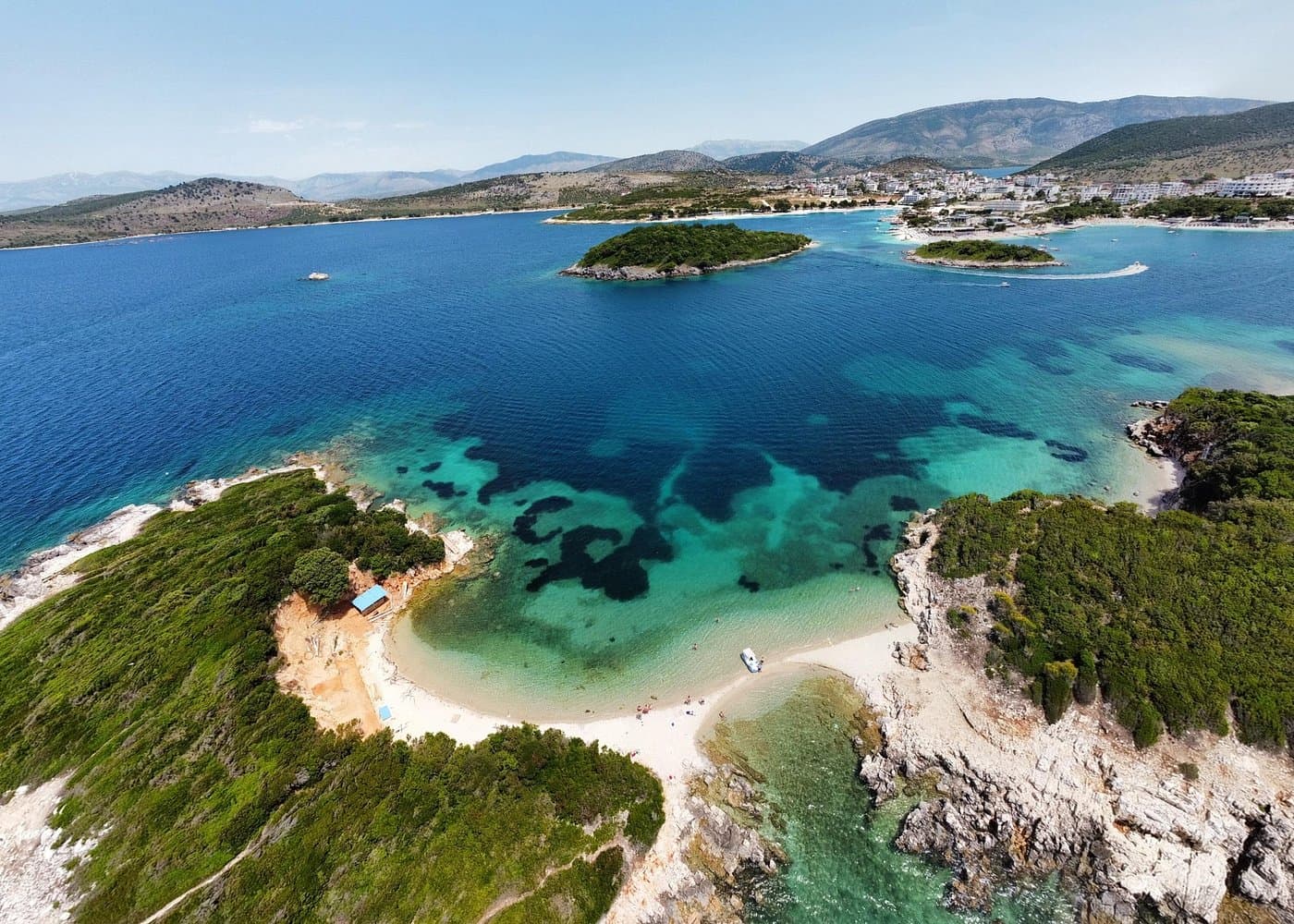 A fast white speedboat cruising across the open sea with islands in the distance during a thrilling island-hopping tour in Ksamil