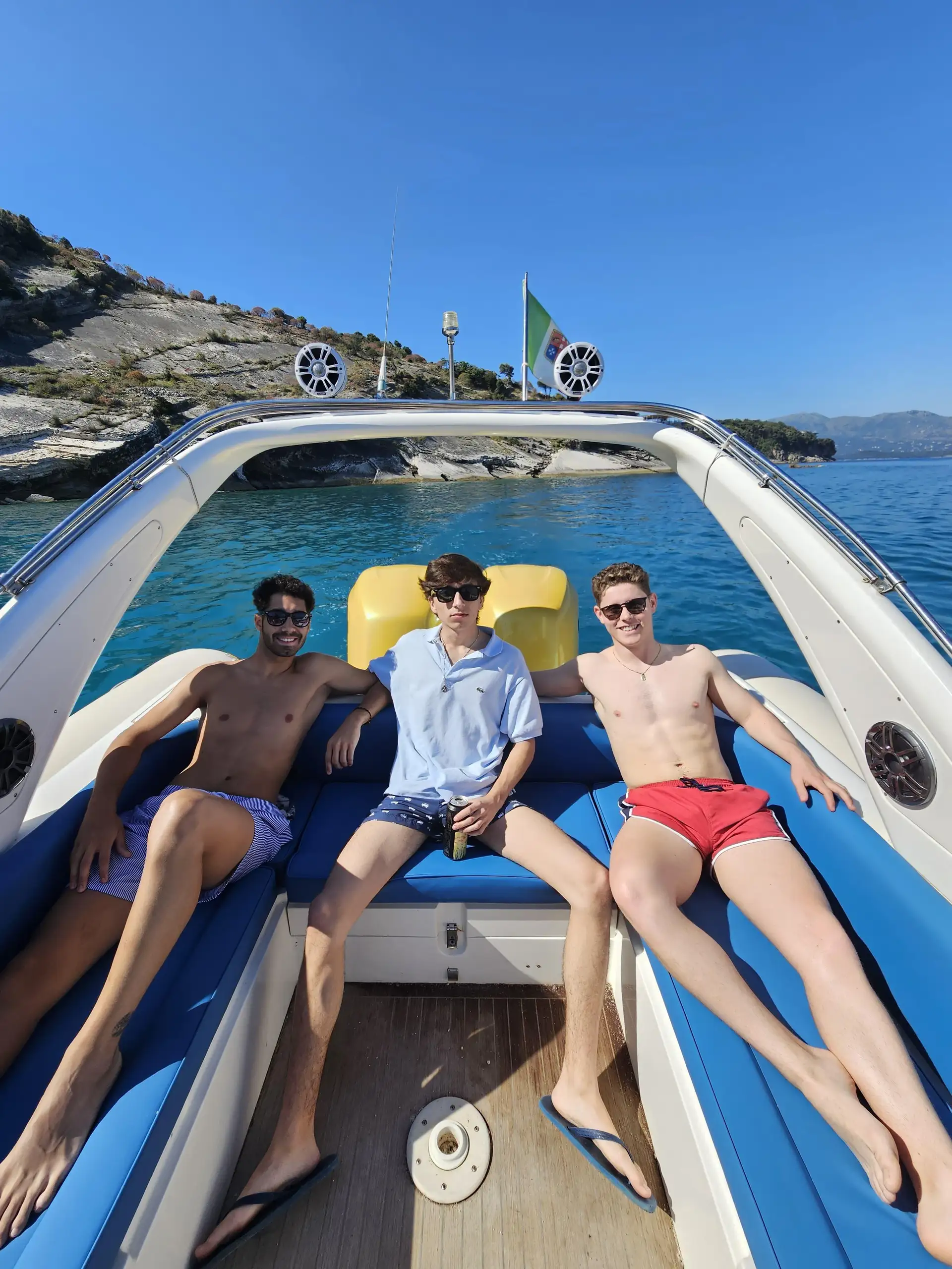 Group of friends relaxing on the deck of a scenic boat tour cruising towards Pigeon Cave and Seagull Beach in Albania