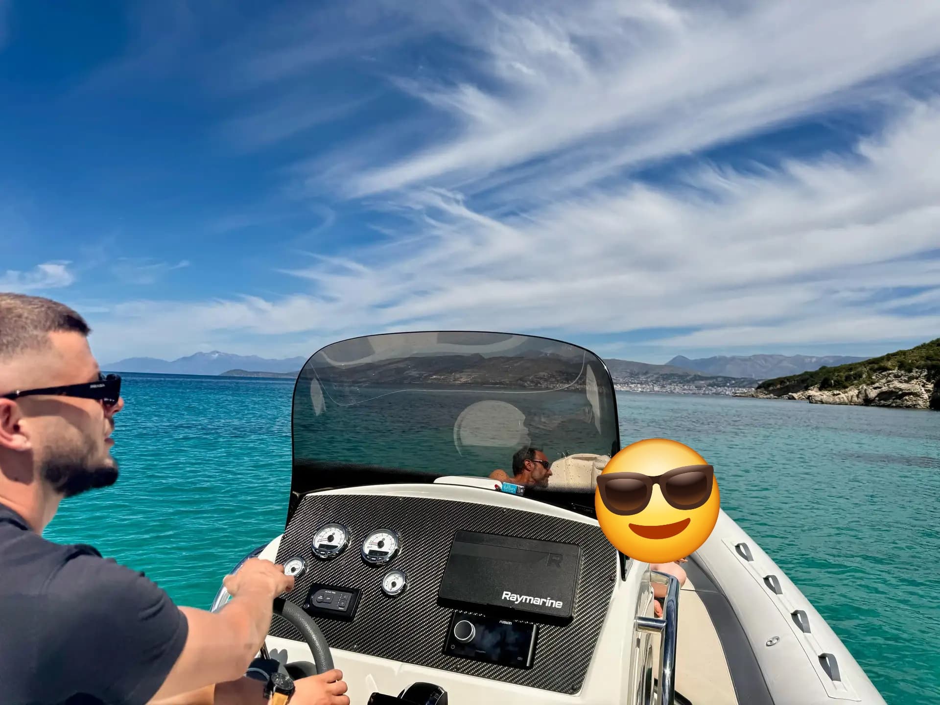 Captain steering a boat through perfectly clear Ionian Sea waters along the beautiful Ksamil coastline