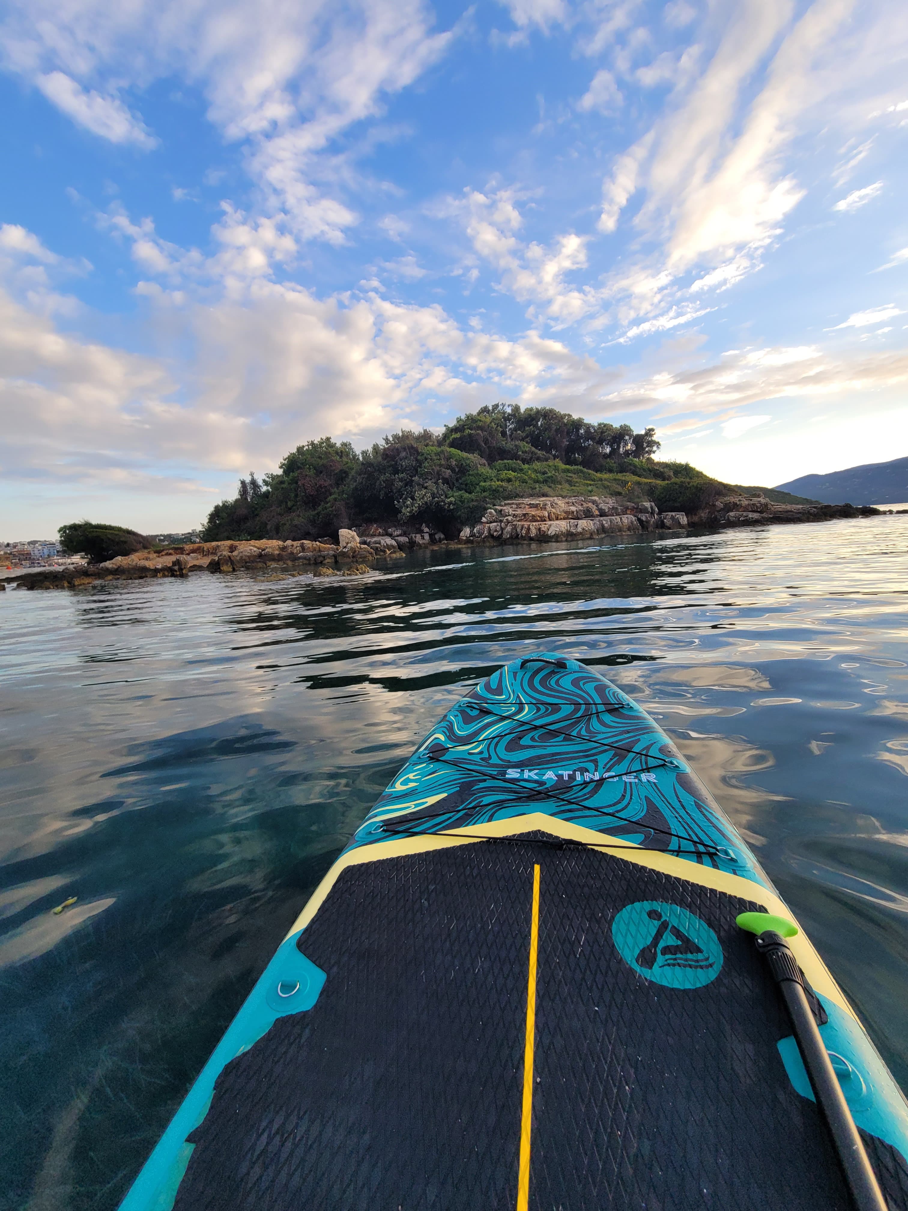 Close-up of a Stand-Up Paddleboarder navigating incredibly transparent turquoise water in the early morning near the Ksamil Islands
