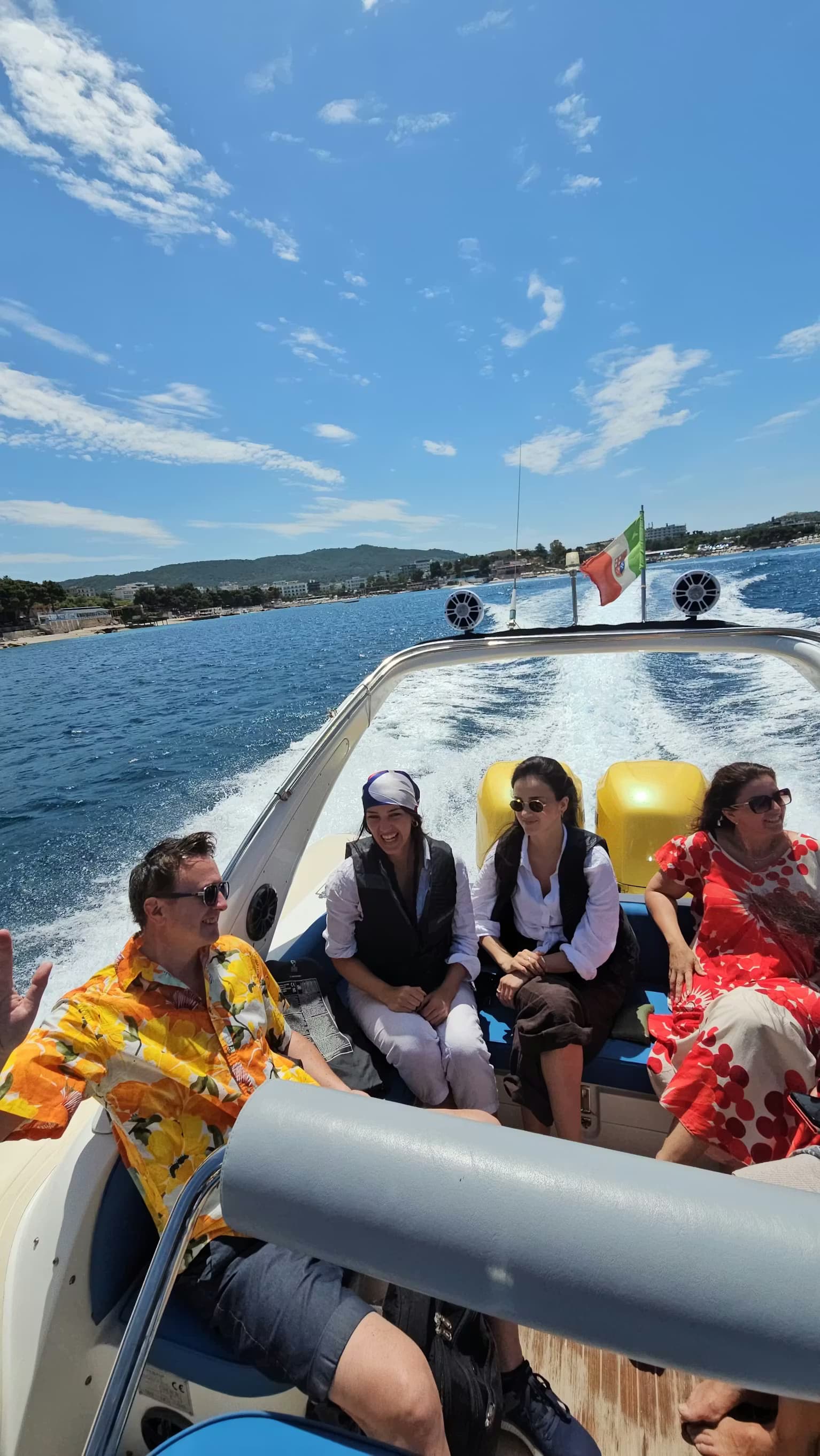 Scenic coastline view of a popular beach in Ksamil with umbrellas and trees, seen from the water during a panoramic boat trip