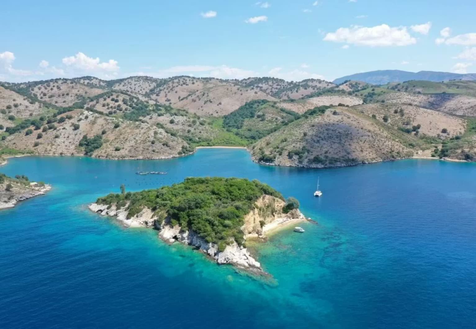 Panoramic aerial view of the lush, secluded Tongo Island surrounded by pristine blue waters on the Albanian Riviera